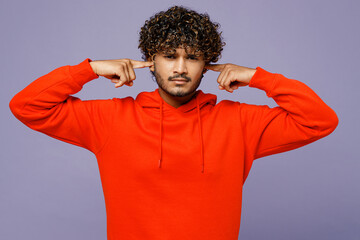 Young dissatisfied sad Indian man wearing red orange hoody casual clothes showing thumb down...