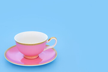 Pink and gold bone porcelain tea cup. Elegant luxury drinking set on pastel baby blue background with copy space. Minimal zen composition.