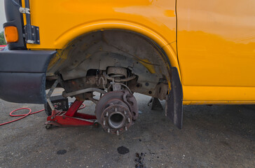 Brakes being repaired on yellow school bus. 