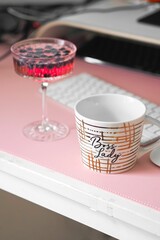 Vibrant pink cocktail with juicy blueberries and a cup on the table with a keyboard background