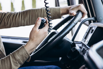Truck driver sitting in the cab of his lorry and using radio transmitter