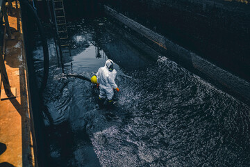 Fototapeta premium Male worker cleaning sump crude oil surface background