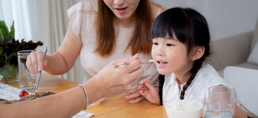 Happiness asian family mother and father and daughter eating food in kitchen together at home, parent and kid sitting dining in living room, bonding and relation, lifestyles and nutrition concept.