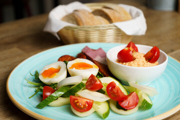 Soft Boiled eggs with vegetables, ham and sausage on a plate