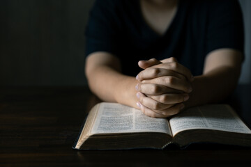 Hands together in prayer to God along with the bible In the Christian concept of faith, spirituality and religion, men pray in the Bible. prayer bible