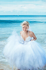 Fototapeta na wymiar Beautiful bride in a white dress on the sea smiling at the groom