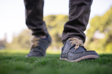 Fototapeta premium Close up of man shoes walking on grass, moving forward concept, business growth, active, relaxing