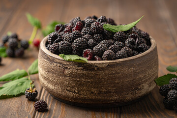 Organic fresh black raspberry in a bowl on dark wooden background