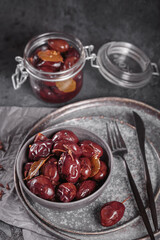 Bowl of pickled plums with spices on rustic wooden background. Clean eating, vegetarian food concept