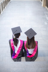 Back of Two friends in graduation caps and gowns