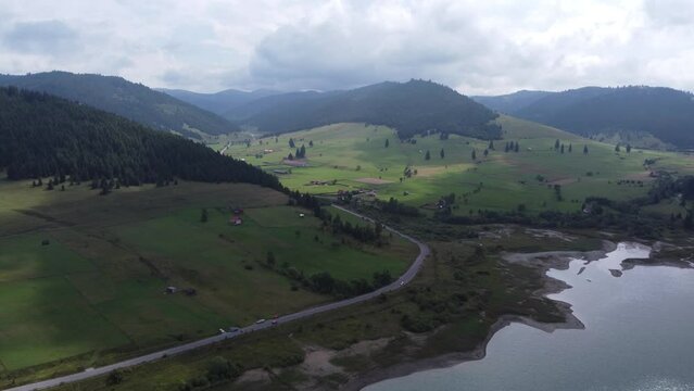 Aerial footage over hillsides and a road in a local community in Romania near Lake Barajul Frumoasa