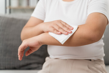 Woman wipes cleaning her arm with a tissue paper towel. Healthcare and medical concept.