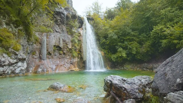 Waterfall between rocks and green trees