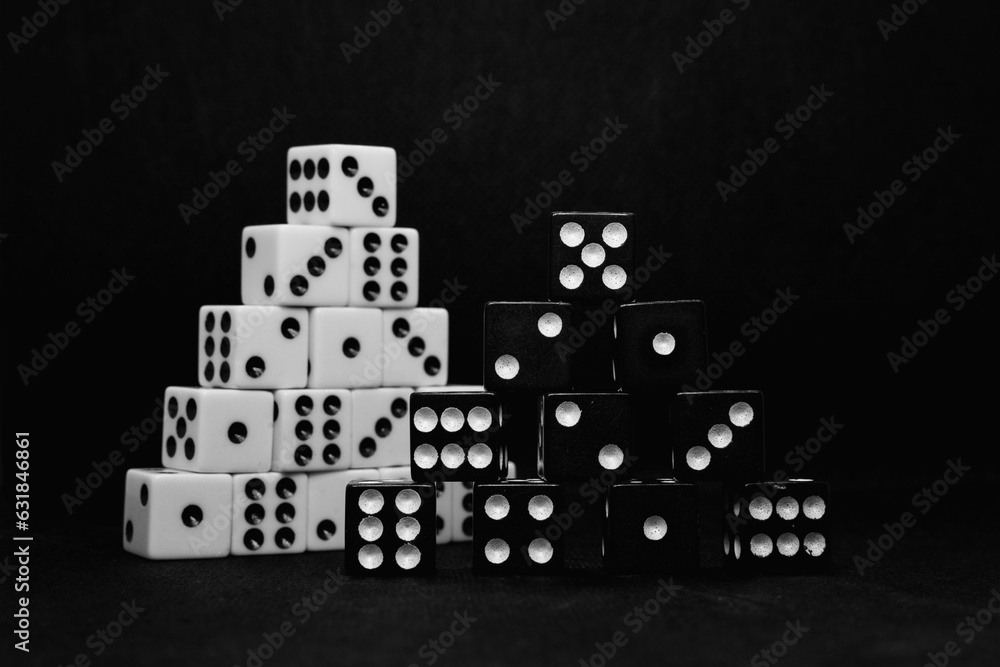 Poster close up of black and white dice stacked in the shape of a pyramid isolated on a black background