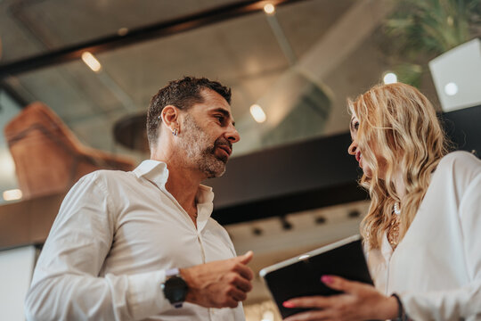 Smiling business colleagues discussing over digital tablet in office