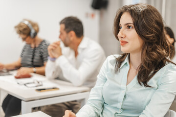 Brunette business girl listening to business presentation at the classroom. Stunning female employee smiling while listening to a presentation