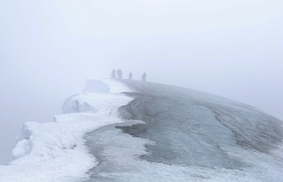 Group of people standing on the cliff in a stormy weather in winter