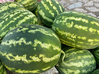 Pile of ripe watermelons for sale, closeup as background. A lot of green striped watermelons at Farmers market counter. Local harvest, organic produce at Laiki agora on streets of Athens, Greece.