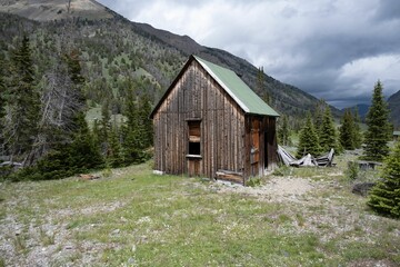 Old, abandoned mining cabin standing in a lush mountainous setting