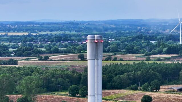 Aerial view of a steel segment tower and large wind turbines and trees