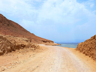 Fototapeta na wymiar Panoramic view of unpaved road in the desert of the Sinai Peninsula. Sandy road on the Red Sea coast. Extreme landscapes and desert routes.