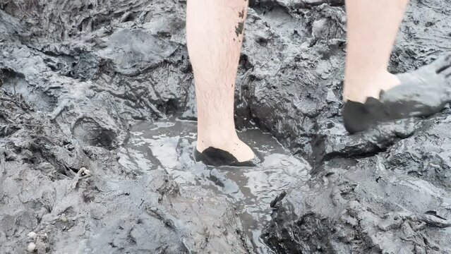 Man walks through the mud. Health therapy and mud bath in natural mud accumulation
