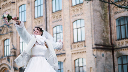 portrait of a beautiful bride, in a white dress, veil and fur coat. bride is spinning, and smiling...