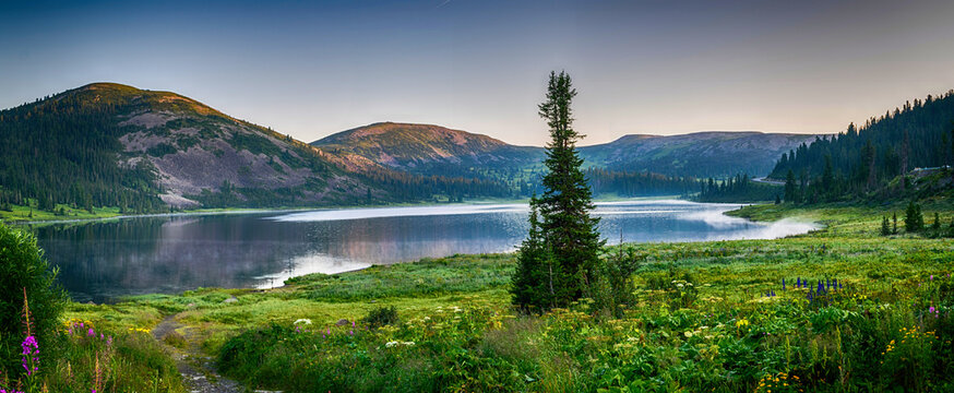 Panoramic landscape, view on mountain lake with hills and green forest during sunrise. Ergaki national park, Siberia, Russia