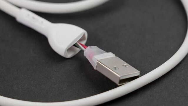 Bitten damaged torn white computer usb cable close up. Rotation