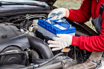 a car mechanic installs a battery in a car. Battery replacement and repair