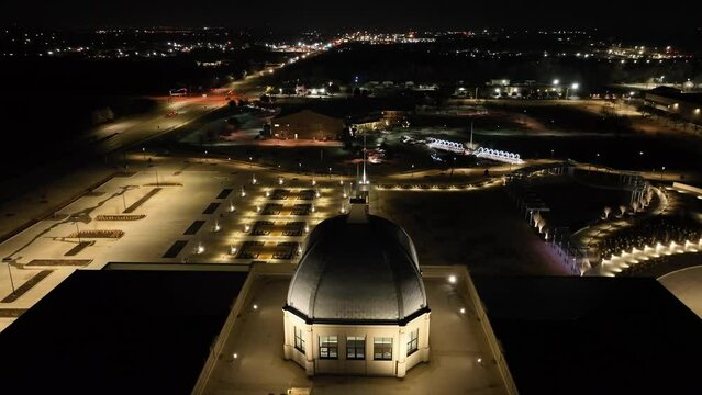 Aerial view of Denton Texas courthouse illuminated by lights at night. Panning downward