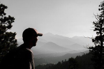 Male hiker wearing a cap and looking at majestic mountains in Estes, Colorado © Luke Davis Producitons/Wirestock Creators