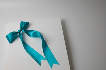 Gift card with a blue ribbon tied around it atop a solid white background