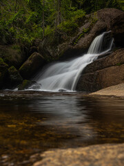 Obraz premium Amazing waterfall hidden deep in Jizera mountains, Czech Republic. Calm and peaceful place with water flowing in cascade river.