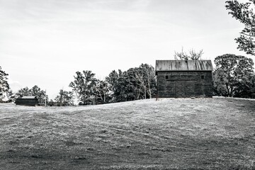 Striking black and white of an old barn situated in a vast expanse of grassy meadow © Brian Dunn/Wirestock Creators