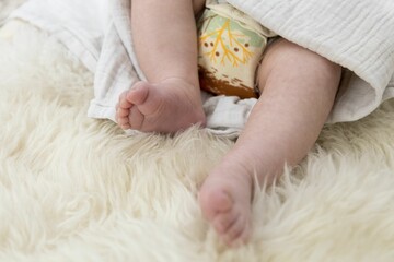 Tiny feet of a newborn baby on a soft, white blanket