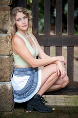 Young Caucasian female kneeling on the ground, posing in a skirt