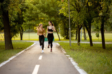 Two pretty young women running on the lane in the park