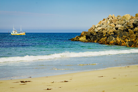 Seascape with fishing boat and stone breakwater