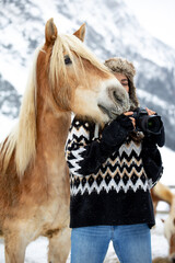 Woman with camera and horse in winter landscape takes photos
