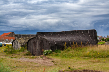 Fototapeta na wymiar Upturned boats used as sheds on Lindisfarne