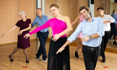 Cheerful man and woman practicing ballroom dances in ballroom
