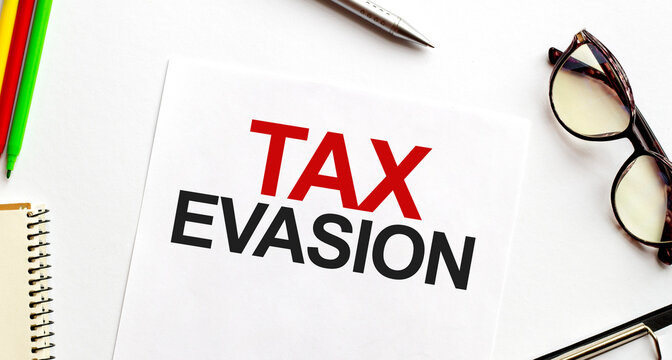 TAX EVASION on paper sheet with glasses and pencils