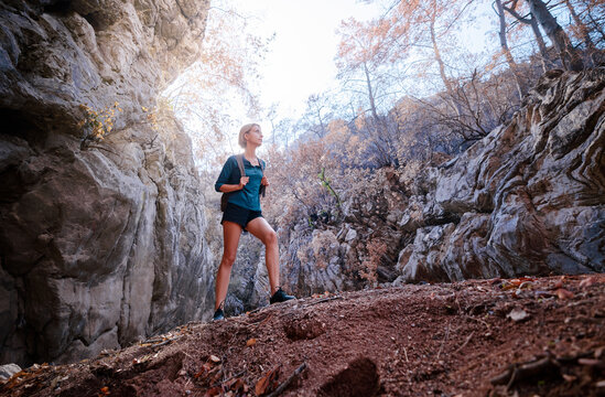 Active lifestyle. Trekking and hiking. Young woman with rucksack in the rocks forest.