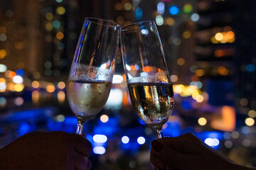 A young couple toasts with champagne at night in Dubai at the Marina Promenade.