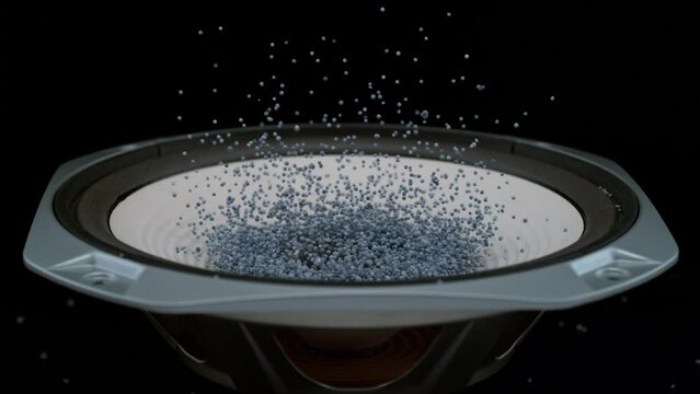 Beads bouncing in speaker in slow motion