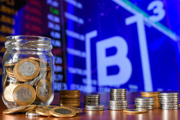 Coins in a glass jar on the background of the stock exchange