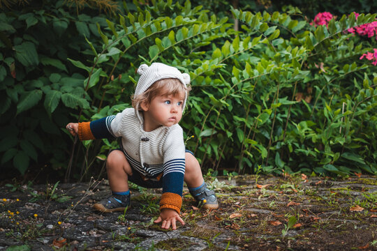 Kind in Superhelden-Pose vor einer gr&uuml;nen Hecke