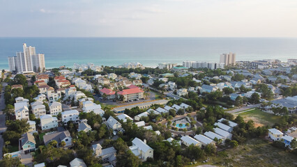 White three-story vacations homes, condo buildings surrounding by lush green trees in beach...