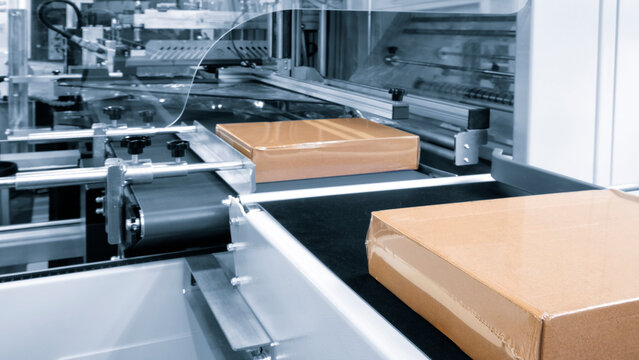 Automatic industrial machine for plastic packaging with light effect of products and food. automated packaging line with plastic film in a light blue scene. machinery product packaging concept